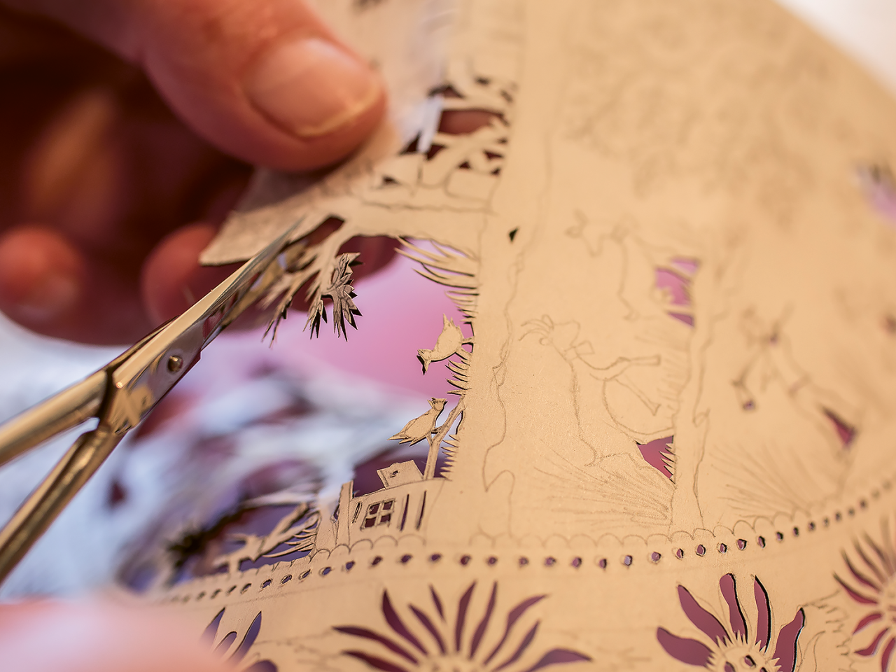 Ein Detailbild einer Schere, die einen filigranen Scherenschnitt ausschneidet.