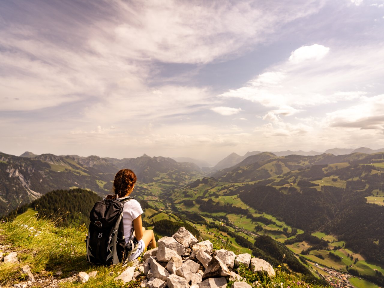Eine Person geniesst den Ausblick auf das Simmental bei sonnig-bewölktem Wetter.