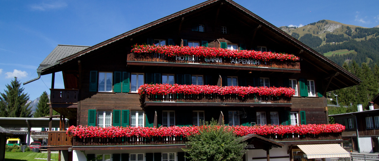 Das Hotel Garni Alpenruh an der Lenk mit schönen roten Granien an den Balkongeländer