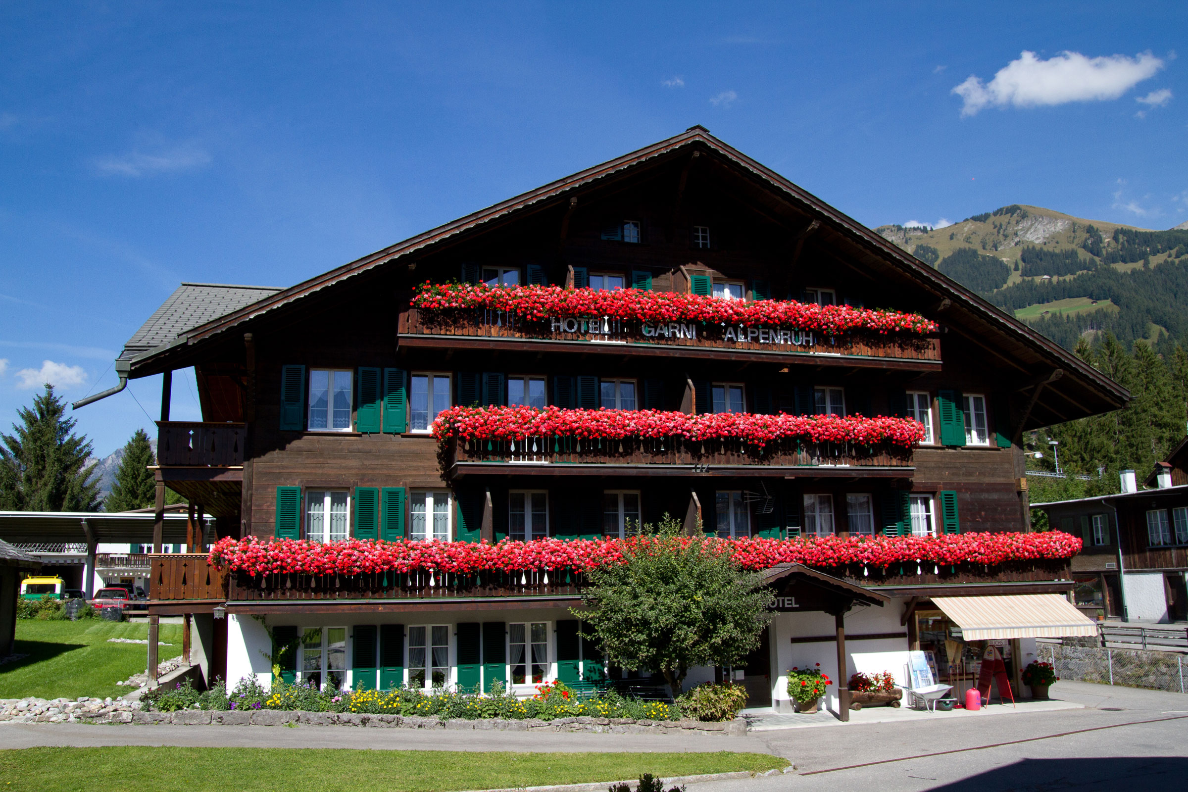 Das Hotel Garni Alpenruh an der Lenk mit schönen roten Granien an den Balkongeländer